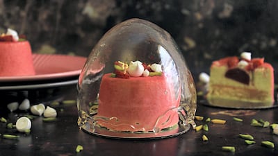 Khan's sugar globe dessert, a pistachio mousse and vanilla cake with a strawberry jam centre, velvet sprayed and topped with strawberries, meringue kisses, and pistachios