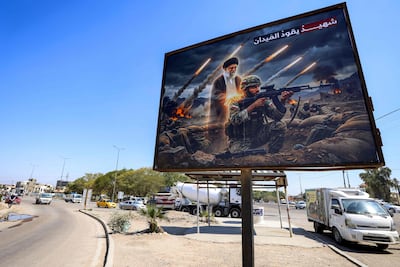 A billboard depicting Ayatollah Ali Khamenei, Iran's assassinated supreme leader, standing behind an Iranian soldier with a caption in Arabic reading 'a martyr leads the battlefield', is displayed along a road in Baghdad, Iraq. AFP