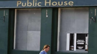A man walks past a boarded-up pub for sale in west London.