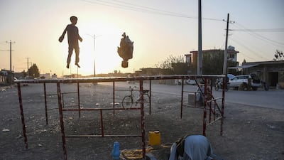 A man prays as children play on a trampoline on the outskirts of Mazar-i-Sharif in northern Afghanistan. AFP