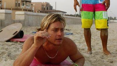 Daniel Van Dooren, left, and Scott Chambers of Surf Dubai demonstrate surfing techniques to students on the beach.