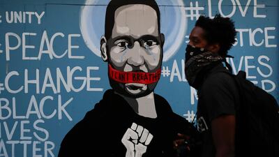 A man walks past a mural depicting George Floyd during a protest over the death of the African-American man, on Sunday, May 31, 2020, in Los Angeles. AP