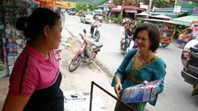 Mu Sochua, right, who is facing defamation charges, speaks to a news-stand vendor in Cambodia.