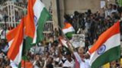 Indian social activist Anna Hazare (C) waves the Indian national flag as he stands on the back of a vehicle outside Tihar Jail in New Delhi on August 19, 2011. Indian activist Anna Hazare has left jail to start a two-week public fast likely to fuel an eruption of angry protests over corruption that has left the government stumbling for a response. Thousands of frenzied, flag-waving supporters cheered the diminutive 74-year-old as he walked from the gates of Delhi's Tihar jail -- his de-facto campaign headquarters since he was taken into police custody three days ago. AFP PHOTO/Sajjad HUSSAIN