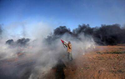 A Palestinian protester covers his face from Israeli tear-gas during clashes with Israeli troops near the border with Israel in the east of Gaza City, 10 August 2018. EPA