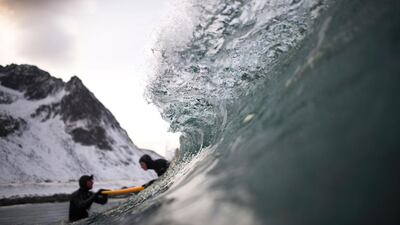 Norwegian surfer Tommy Olsen is seen in the water as he gives a surfing lesson to beginners in Flakstad.