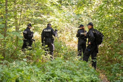 Police search a wooded area after the discovery of the body last August. Getty