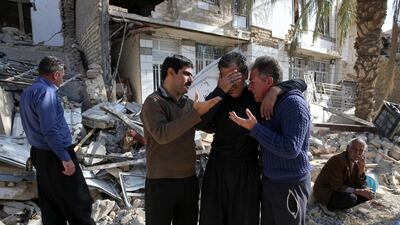 Earthquake survivors mourn in front of destroyed houses in Sarpol-e-Zahab in western Iran, Wednesday, Nov. 15, 2017. Survivors are waiting for badly needed aid, three days after a powerful earthquake along the Iraq border killed hundreds and left thousands injured. (AP Photo/Vahid Salemi)