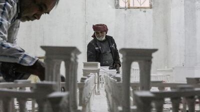 Ali Saleh, foreground, helped by an assistant, pieces together his model of ancient Palmyra, in al-Bab, northern Syria. His family say he has lost his home and three sons and daughter due to the 10 years of conflict in Syria. AFP