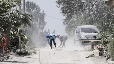 Men clean volcanic ash from the street after Mount Sinabung volcano spewed thick volcanic ash across the area the day before in Karo, North Sumatra. Kadri Boy Tarigan / AFP