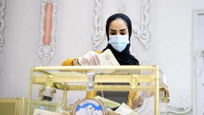 A Kuwaiti woman wearing a protective mask cast her vote at a polling station in Kuwait City. EPA