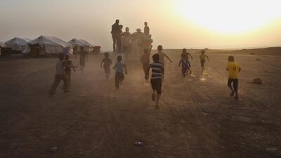 Displaced Iraqi boys run behind a truck distributing meals for a communal meal for Muslims to break their fast on the first day of Ramadan on June 29, 2014 , at a camp for displaced Iraqis who fled from Mosul and other towns, in the Khazer area outside Erbil, northern Iraq. Hussein Malla/AP Photo