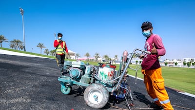 Workers apply paint to the tarmac. Victor Besa / The National