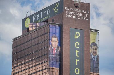 late Venezuelan President Hugo Chavez (L), current President Nicolas Maduro (R) and petro's crypto-currency logo on a building in Caracas, Venezuela. EPA