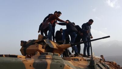 Protesters stand on a Turkish tank after they stormed a Turkish military camp near Dohuk, Iraq January 26, 2019. Reuters
