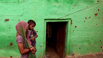 An Indian villager carries a child past a house where four members of a family were reported to have been killed in cross-border firing between Indian and Pakistani soldiers at Mashe de Kothe village in the Arnia sector near the India-Pakistan border. Stringer / AFP