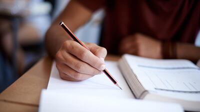 Closeup shot of a young man writing on a note pad