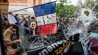 A protester holds a French tricolore flag with an anti-Macron slogan outside a destroyed McDonald's fast food restaurant. Unions called for marches to protest against government reforms in the public services. EPA/CHRISTOPHE PETIT TESSON