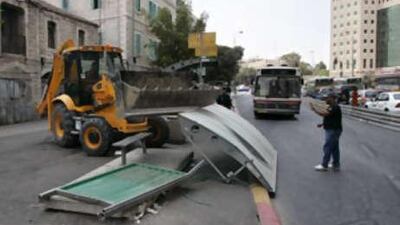 A large tractor removes a bus station which was destroyed in a deadly bulldozer rampage driven by a Palestinian man the previous day in Jerusalem's busy Jaffa Road.