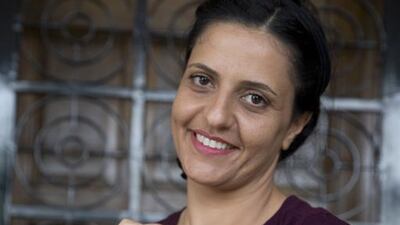 The Palestinian agriculturalist, who is also a writer and photographer, and holds jars of heirloom seeds that include spinach, hummus and chard.