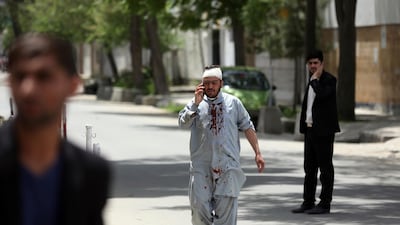 An Afghan injured man walks as he talks with his mobile cell phone after a huge explosion in Kabul, Afghanistan. AP Photo