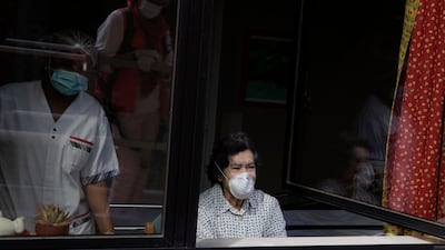 Michelle Ullens reflected in a window visits her friend Parvine Djazayeri via a crane platform from the fourth floor window at the La Cambre senior living home in Watermael-Boitsfort, Belgium. AP Photo