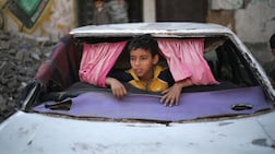 A displaced Palestinian child plays inside a car destroyed during the Israel-Hamas war in the Bureij refugee camp, in the central Gaza Strip. AFP