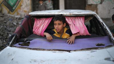 A displaced Palestinian child plays inside a car destroyed during the Israel-Hamas war in the Bureij refugee camp, in the central Gaza Strip. AFP