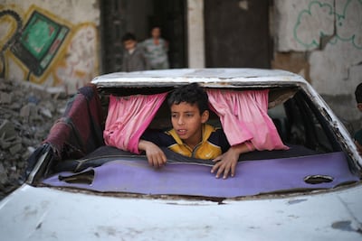 A displaced Palestinian child plays in bashed-up car in Bureij refugee camp, central Gaza. AFP