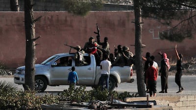 In this photo taken from the Turkish side of the border between Turkey and Syria, in Akcakale, Sanliurfa province, southeastern Turkey, Turkish-backed Syrian opposition fighters celebrate in Tal Abyad, Syria. State-run Anadolu news agency reported Tal Abyad had fallen to a Turkish military offensive on Sunday. Even after the announcement, sporadic gunfire and the occasional mortar round could still be heard in the town, which is on the border with Turkey, while smoke could be seen rising from several points in the town. AP Photo