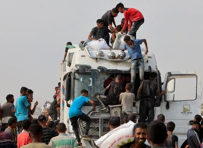 Palestinians scramble to collect aid supplies from trucks in Gaza. Reuters
