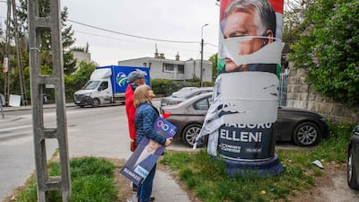 A couple carrying an election banner for Hungary's Tisza party look at a vandalised campaign poster for outgoing Prime Minister Viktor Orban, in Budapest. Mr Orban conceded defeat after Tisza's landslide election victory. AFP