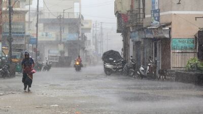 A person walks down a street during heavy rain in Mandvi. EPA