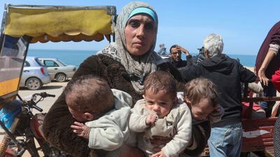 A Palestinian woman carries her triplet children as she flees an Israeli raid at Al Shifa Hospital, in Gaza city. Reuters