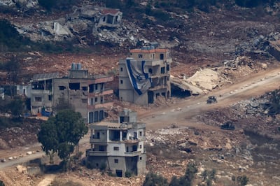 An Israeli military vehicle drives past a damaged building draped with a large Israeli flag in southern Lebanon. Reuters