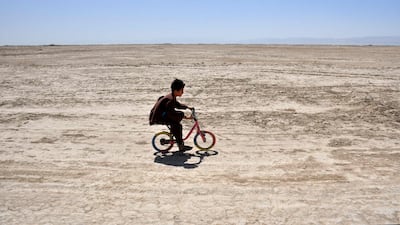 TOPSHOT - An Afghan child rides his bicycle along a deserted street in the drought-ridden village of Bolak at Chahar Bolak district, Balkh province on July 10, 2025. (Photo by Atif Aryan / AFP)