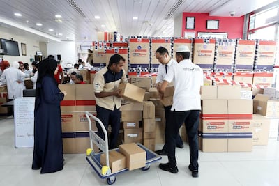 Members of the Universal Hospital Rescue Team in Abu Dhabi pack essential items such as clothing, food, medicine, blankets and baby items into aid boxes ready to be flown to Kerala flood victims. Pawan Singh / The National