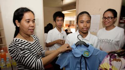 Tess Sarmiento, left, shows students their new uniforms that Etihad Airways donated to the PCF Students. Mike Young for the National
