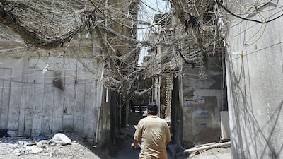 An Iraqi man rides a bicycle beneath a web of electric wires in the Syed Sultan Ali area of the capital Baghdad, on July 13, 2020, used to draw electricity from private generators due to an unreliable national electricity supply amid high temperatures. AFP