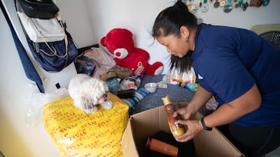 Sharon Toribio, with Max, her employer’s pet, watching on, as she packs Christmas gifts for family in the Philippines. Leslie Pableo for The National