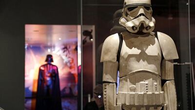 A stormtrooper costume is displayed with Darth Vader behind. AP