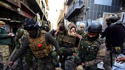 Iraqi security forces help an injured soldier during clashes on Rasheed Street. EPA