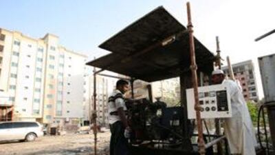 Workers operate the generator to supply electricity to a building in Ajman.