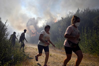 People run to escape the flames from a wildfire near the village of Melon, north-western Spain, which is entering its third week of heatwave alerts. AFP