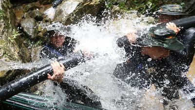 Thai soldiers try to connect water pipes that will help bypass water from entering a cave where 12 boys and their soccer coach have been trapped since June 23. Sakchai Lalit / AP