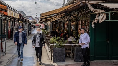 A restaurant worker waits for customers alongside an outdoor dining area in the Naschmarkt in Vienna, Austria. Bloomberg