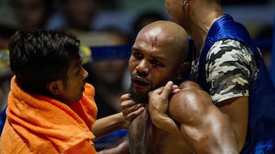 To go with MYANMAR-SPORT-BOXING,FEATURE by Athens Zaw Zaw This photo is taken on December 20, 2015 shows Lethwei martial arts fighter, US national Cyrus "Black Dynamite" Washington (C), reacting following a bloody blow to his face by home champion Tun Tun Min during their bout at the Thein Phyu boxing stadium in Yangon. A roar erupted at the Yangon ring as the home champion ploughed a right hook into his American opponent's face, crumpling him to the canvas in the opening round of the bone-crunching kickboxing bout. With head-butts among the array of painful blows permitted, Lethwei pugilists say their sport is the hardiest member of Southeast Asia's kickboxing family -- even more brutal than Thailand's better known Muay Thai. AFP PHOTO / Ye Aung THU / AFP / Ye Aung Thu