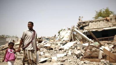 A man and his daughter displaced by fighting between the army and militants, survey a destroyed neighbourhood in the Yemeni city of Zinjibar, capital of Abyan province.