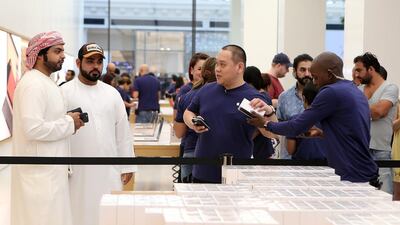 Customers buy the iPhone 7 at the Apple store in Dubai's Mall of the Emirates. The company shipped a record number of smartphones in the fourth quarter despite a critical panning of the phone. Pawan Singh / The National
