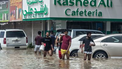 People wade throuh water on a flooded road in Fujairah. Antonie Robertson / The National